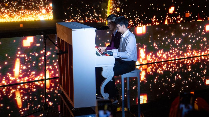 智能仿生手使用者古月與少年鋼琴家舒海峰合奏。主辦方供圖